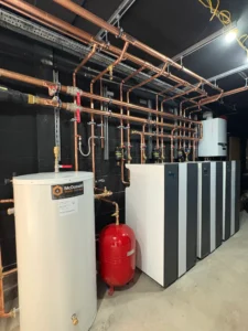 Ground source heat pump system installed in a plant room with cylinders, buffer tanks, and copper pipework